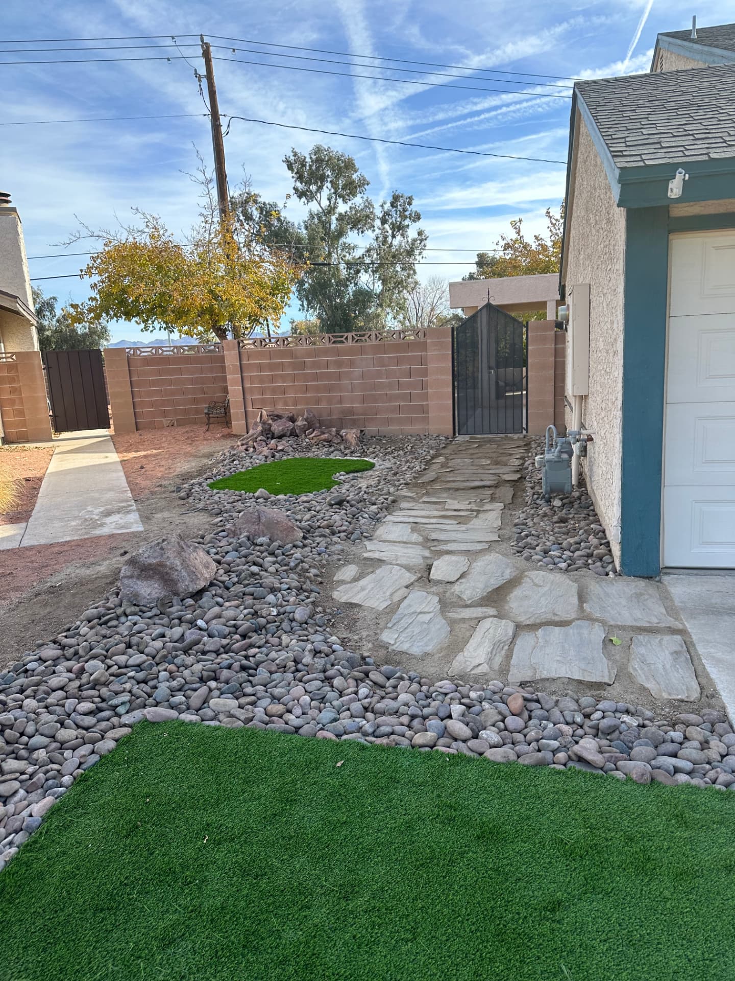 Flagstone walkway to the side gate with dry creek river rock and turf