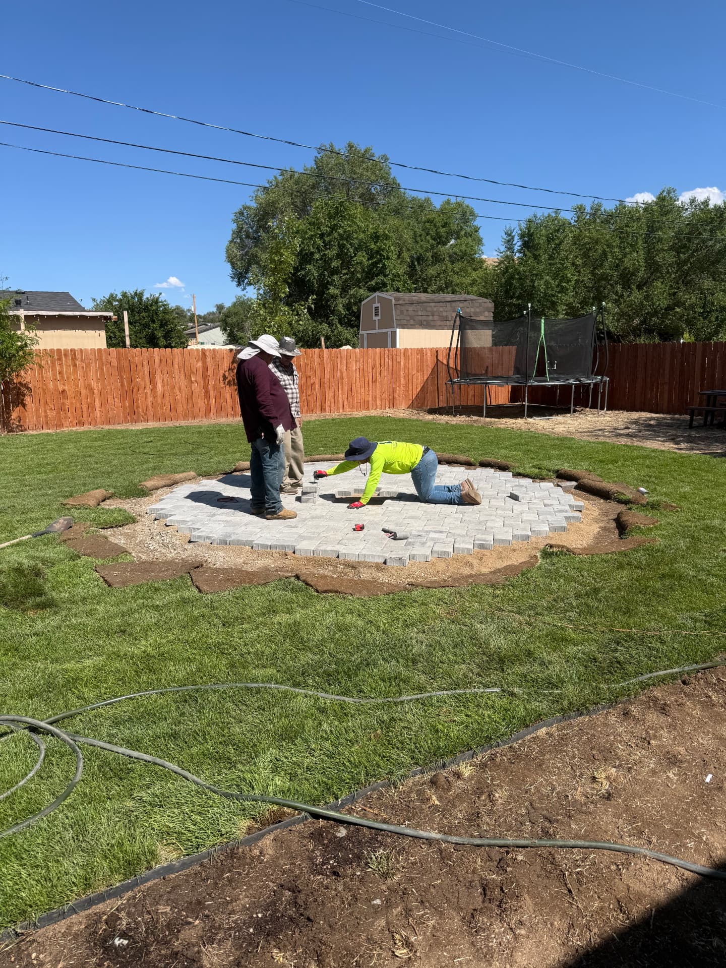 Crew setting pavers and checking layout on the new patio