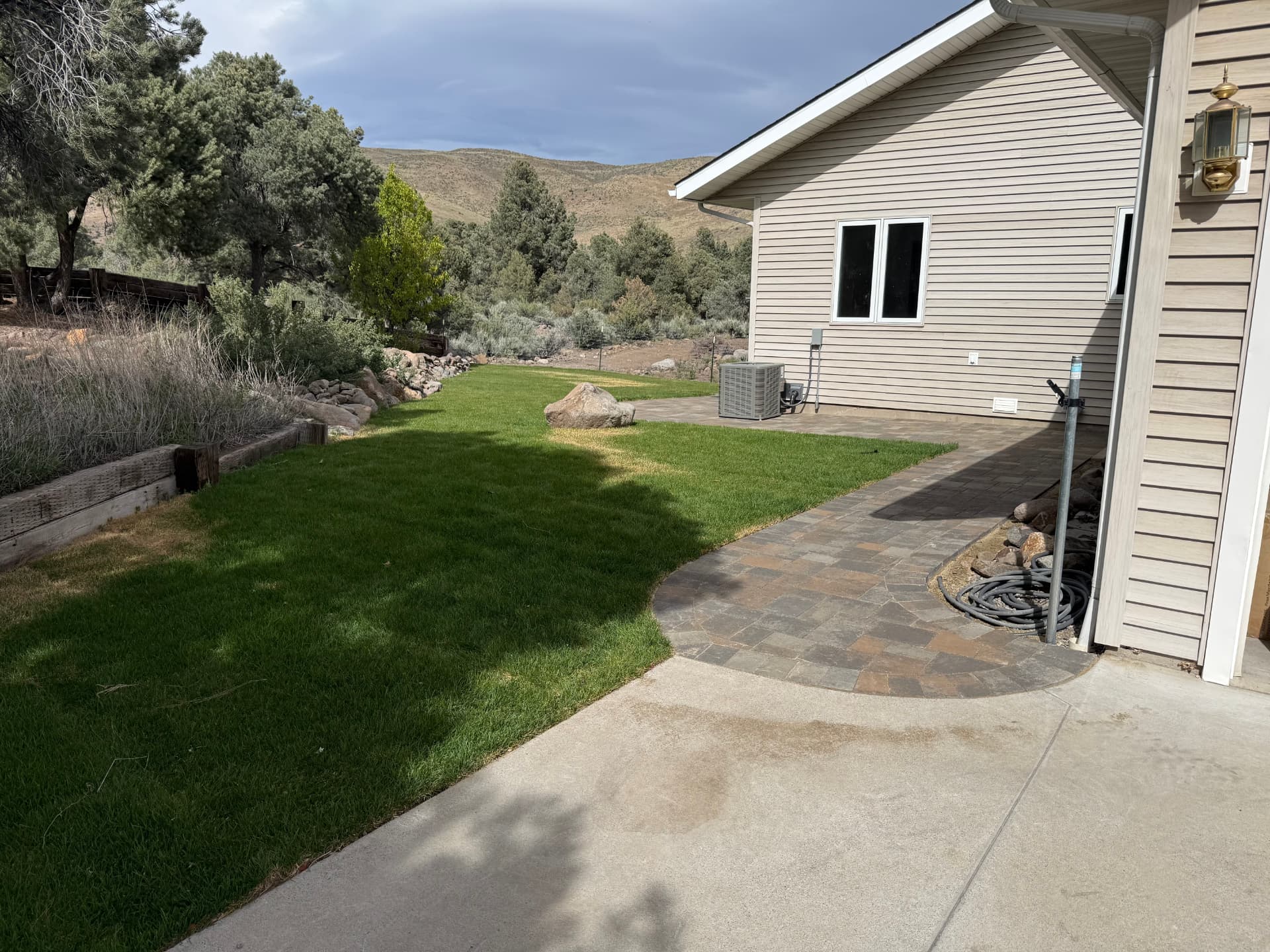 Completed side yard paver patio with fresh sod lawn