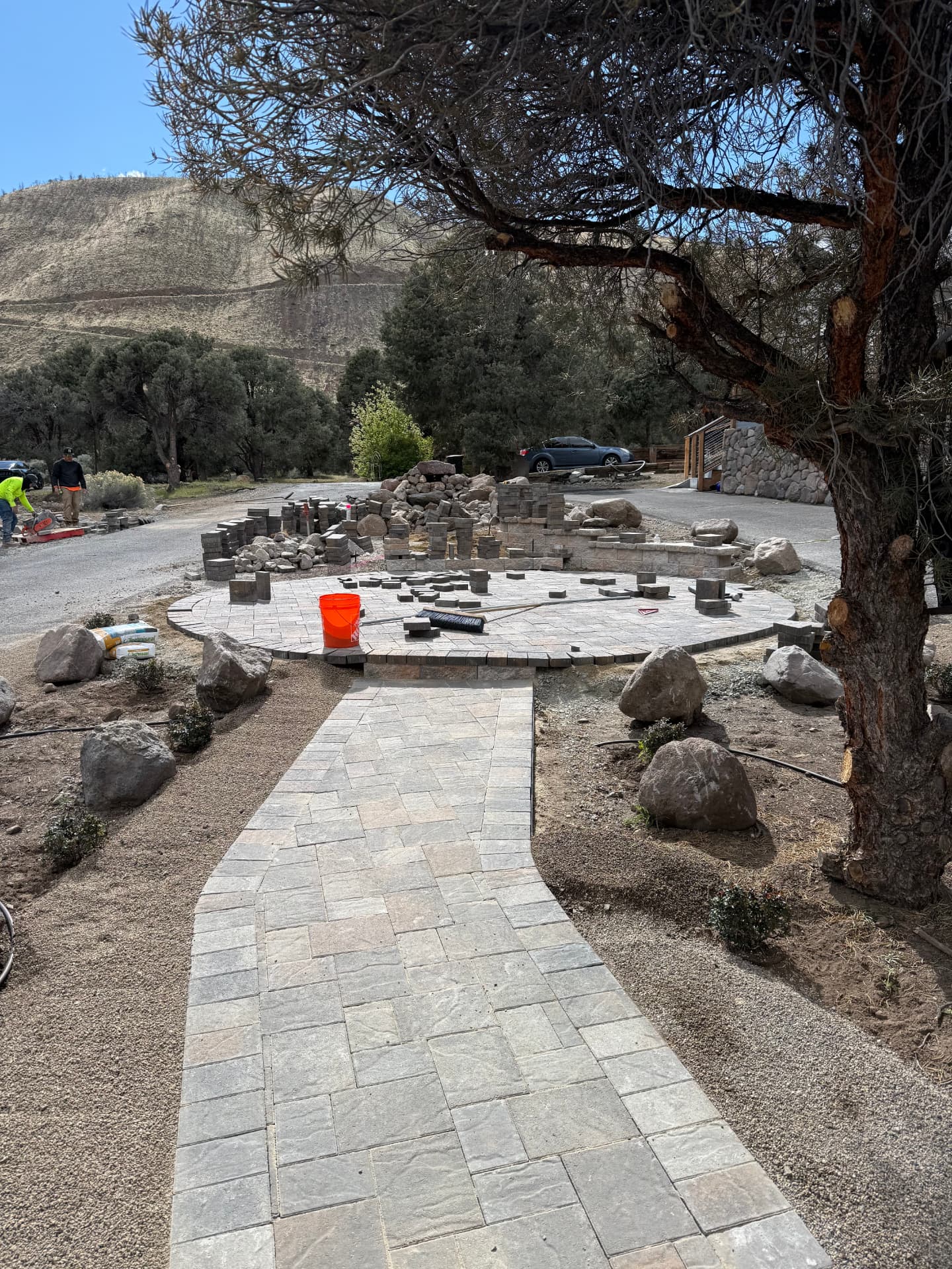 Circular paver patio and herringbone walkway framed by boulders