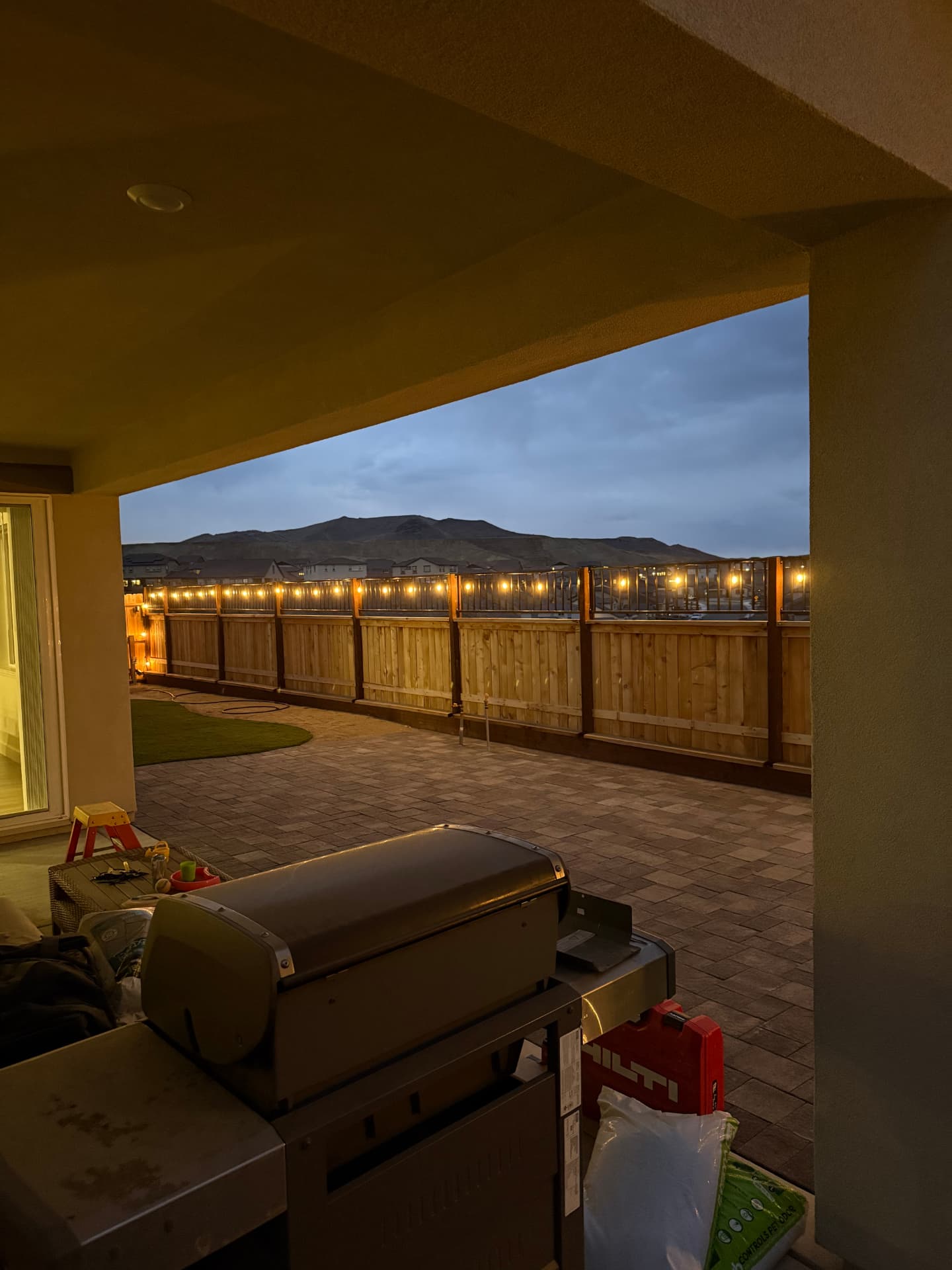Covered patio at dusk overlooking the finished paver backyard