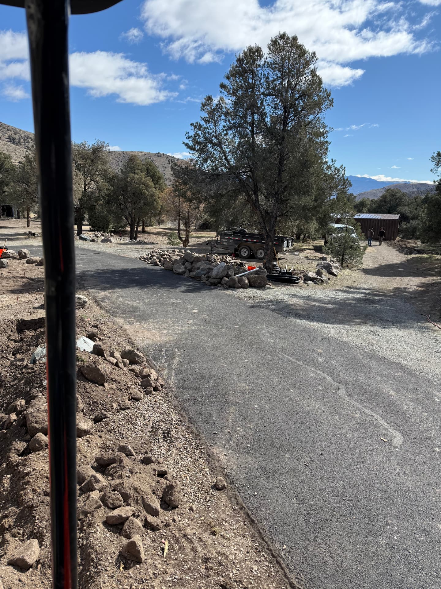 Excavated soil piled beside the driveway with rock and material staged