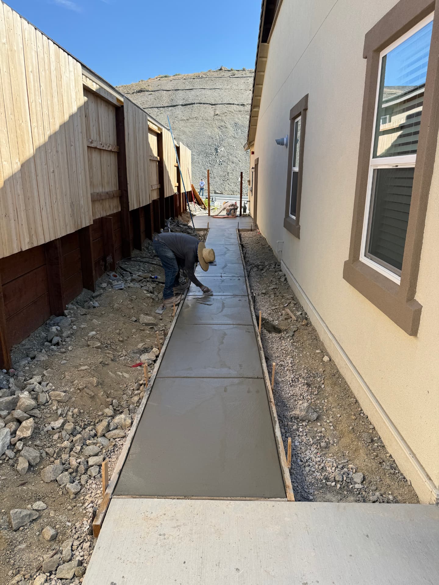Concrete walkway being finished along the side of the house