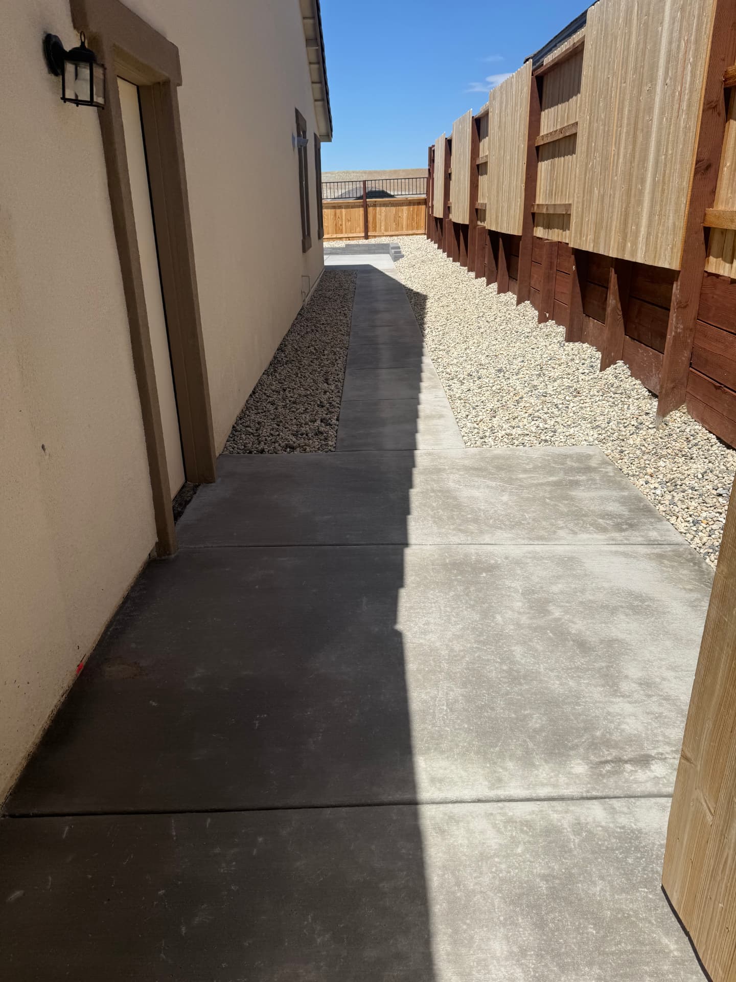 Wide concrete side yard path leading back to the patio