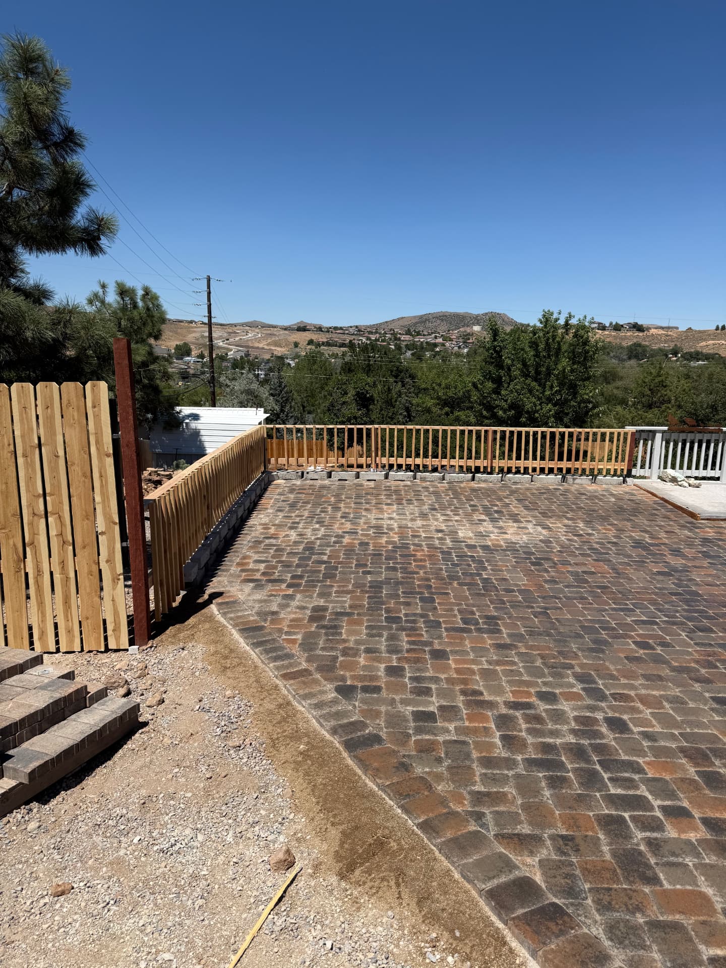 Wide view of completed paver patio, cedar fence, and Reno valley backdrop