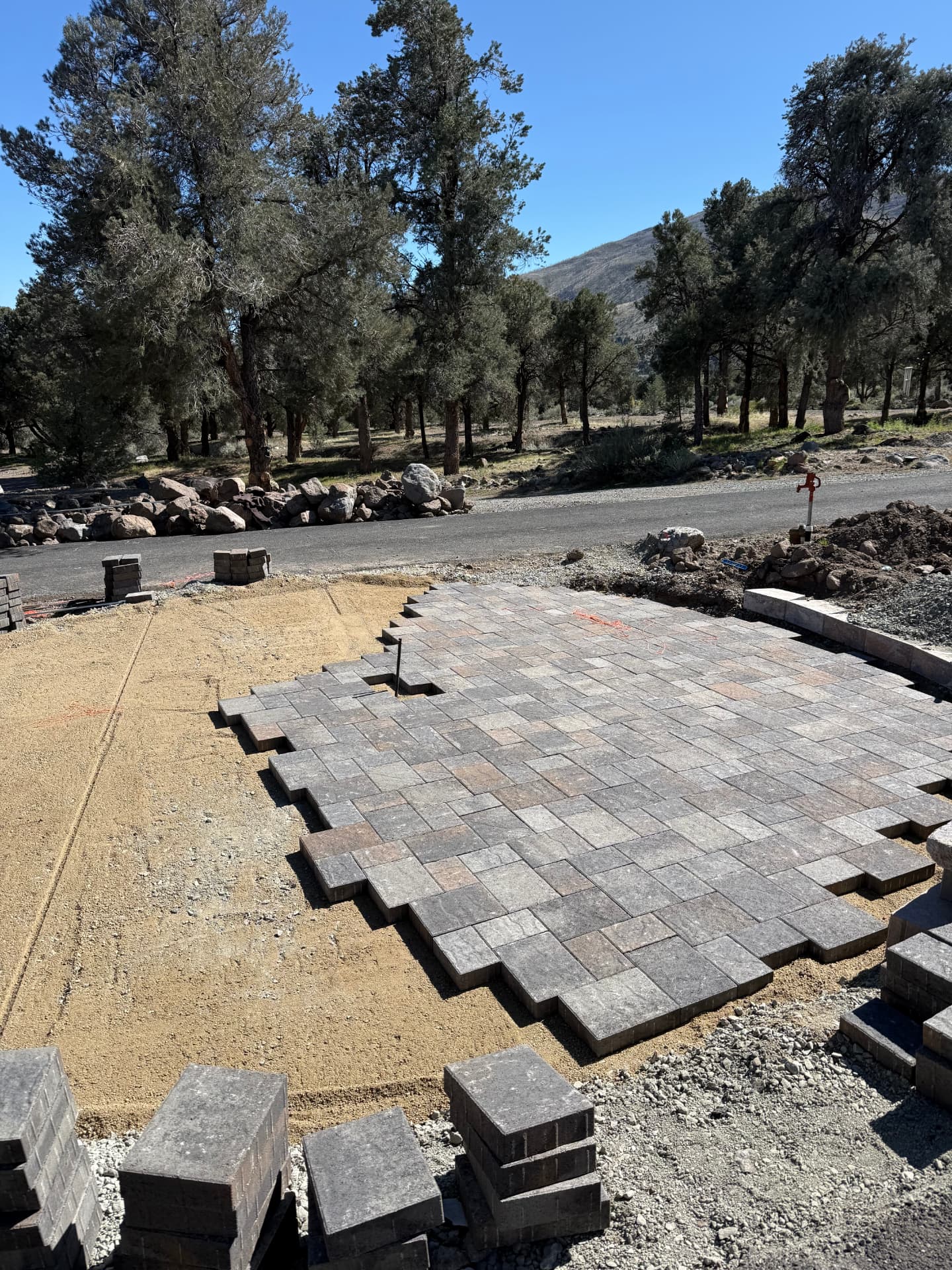 Completed paver pad by the roadside with new wall cap and border