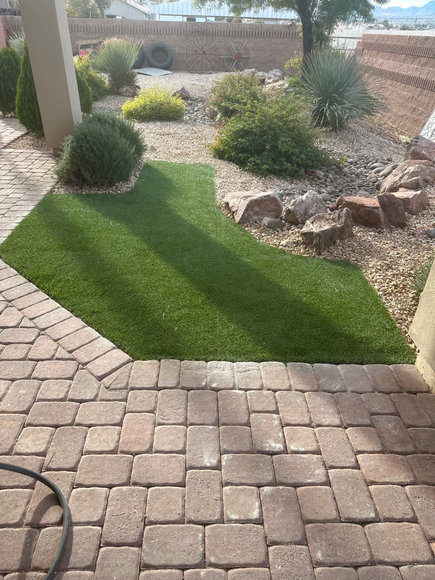 Turf lawn meeting the paver patio with boulder and gravel landscaping