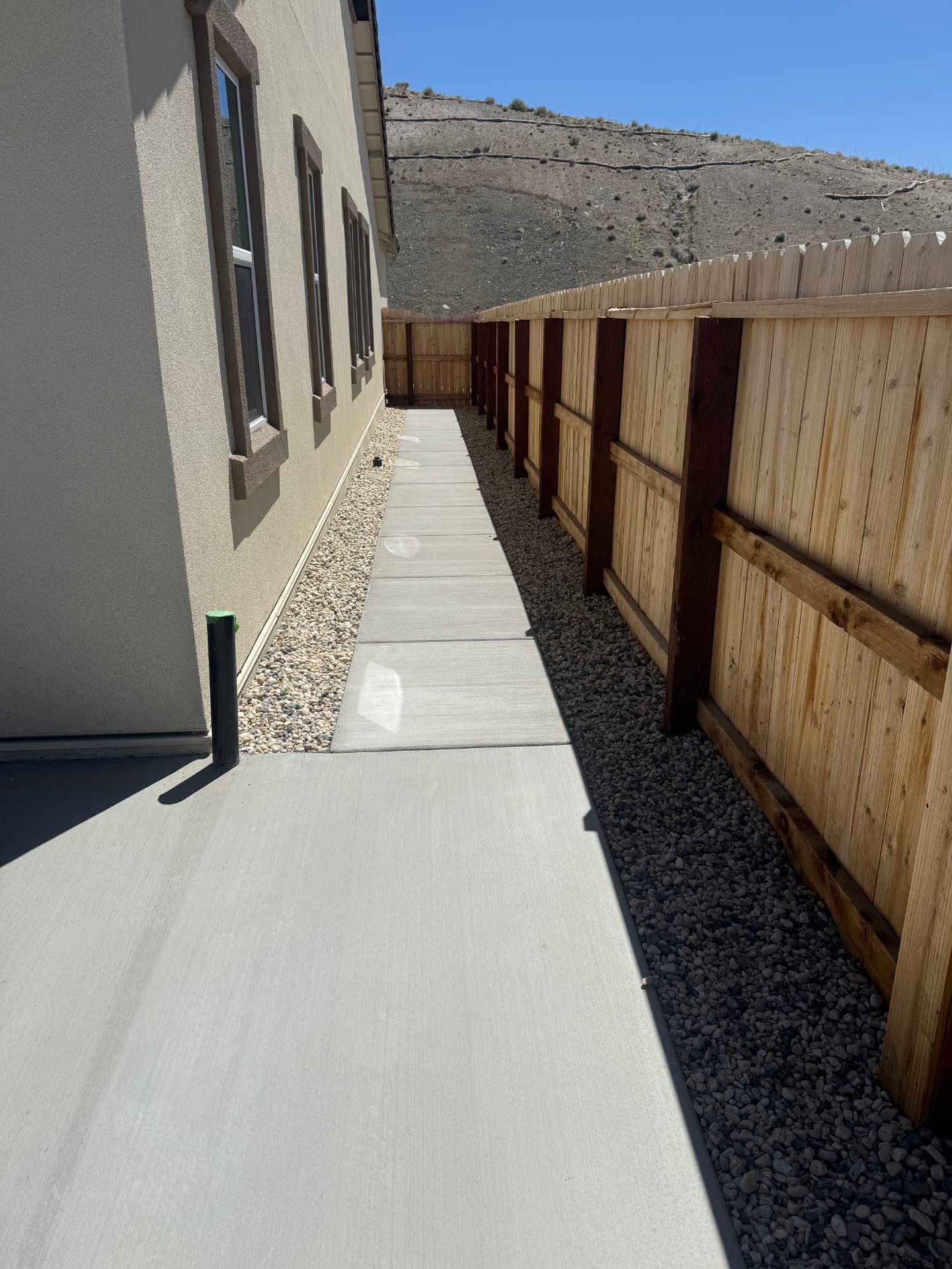 Completed side yard concrete path with dual-tone rock beds