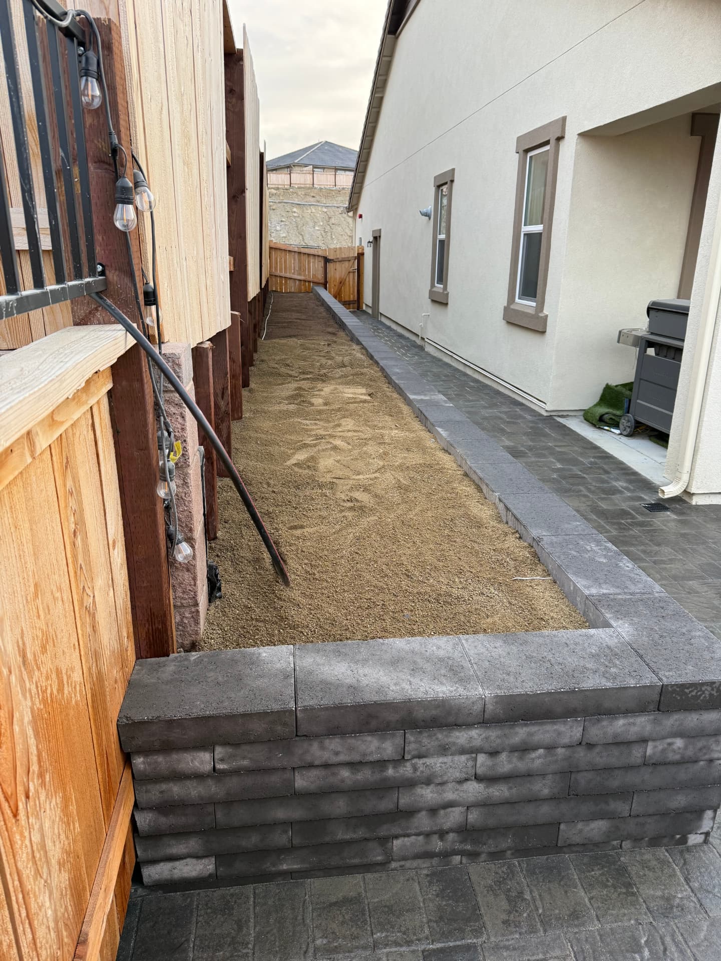 Paver walkway and raised planter wall along the side yard
