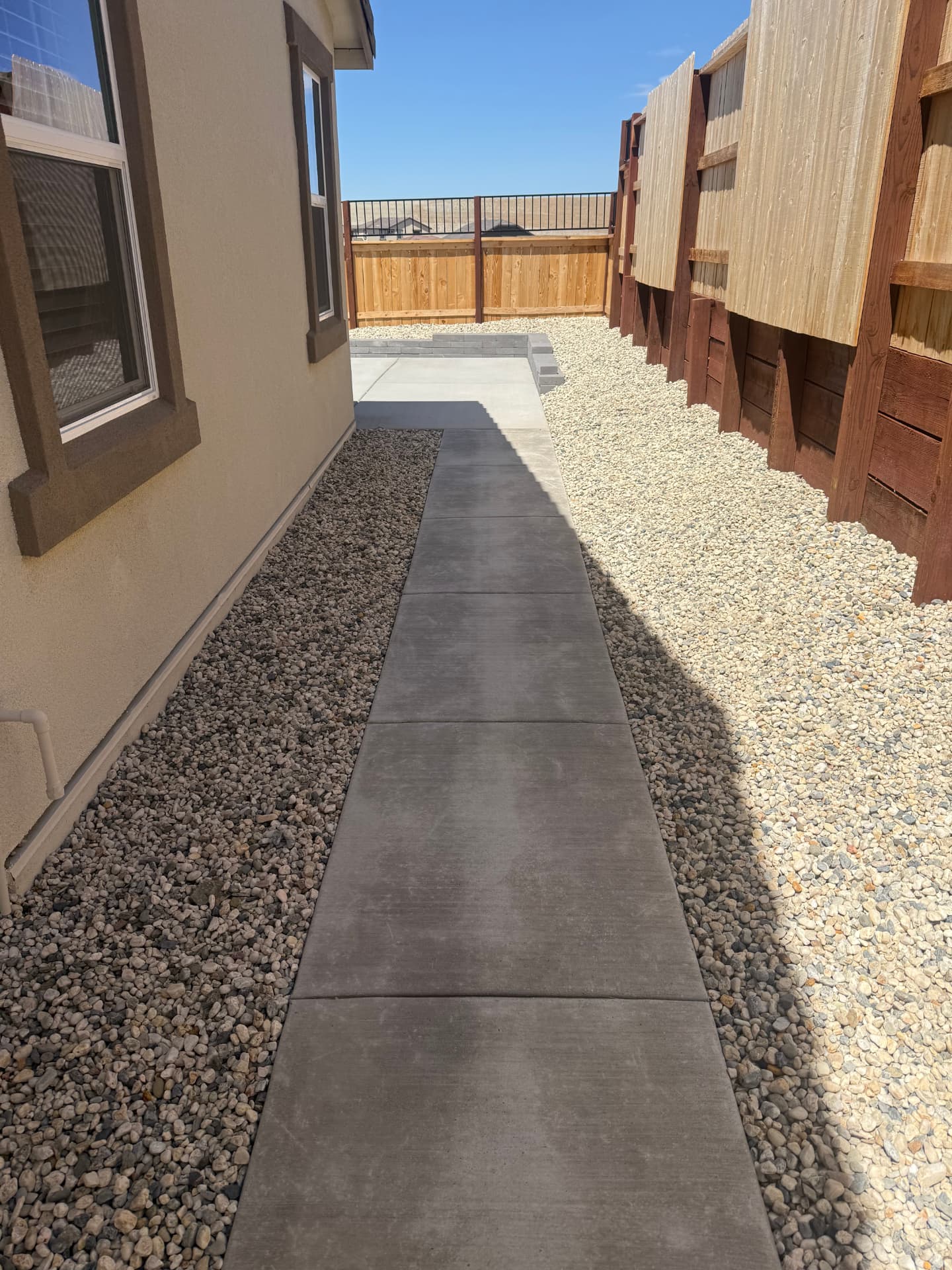 Concrete walkway bordered by contrasting gravel beds