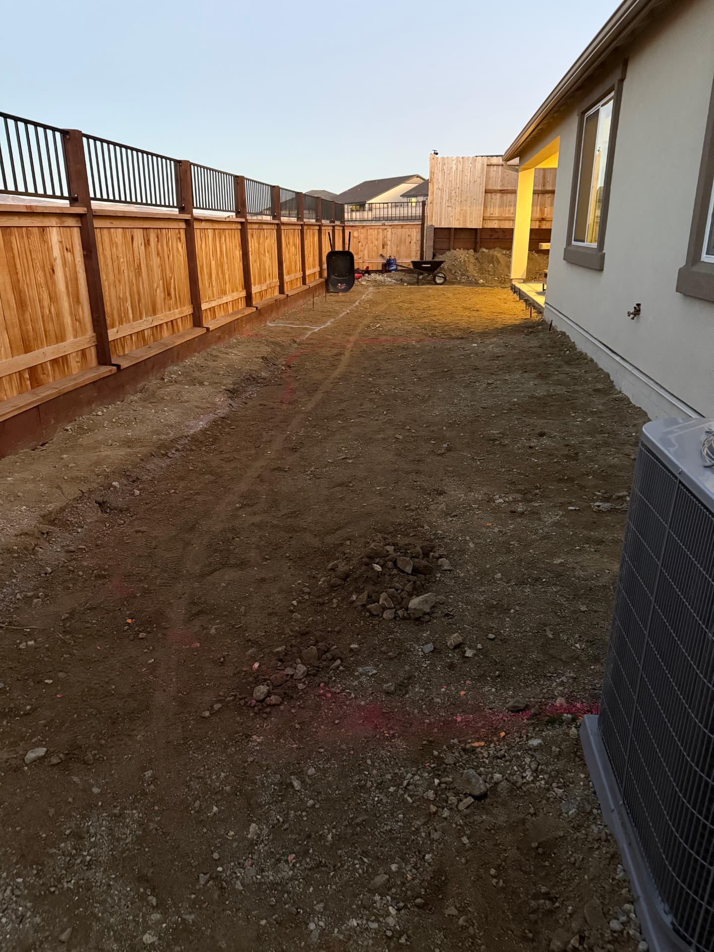 Long backyard dirt area at dusk before hardscape installation