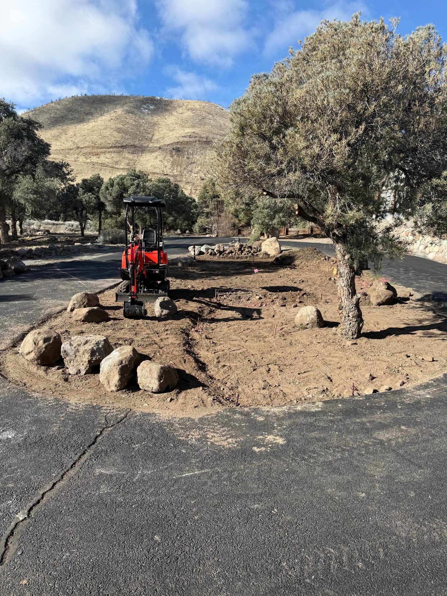 Mini excavator reshaping the circular driveway island