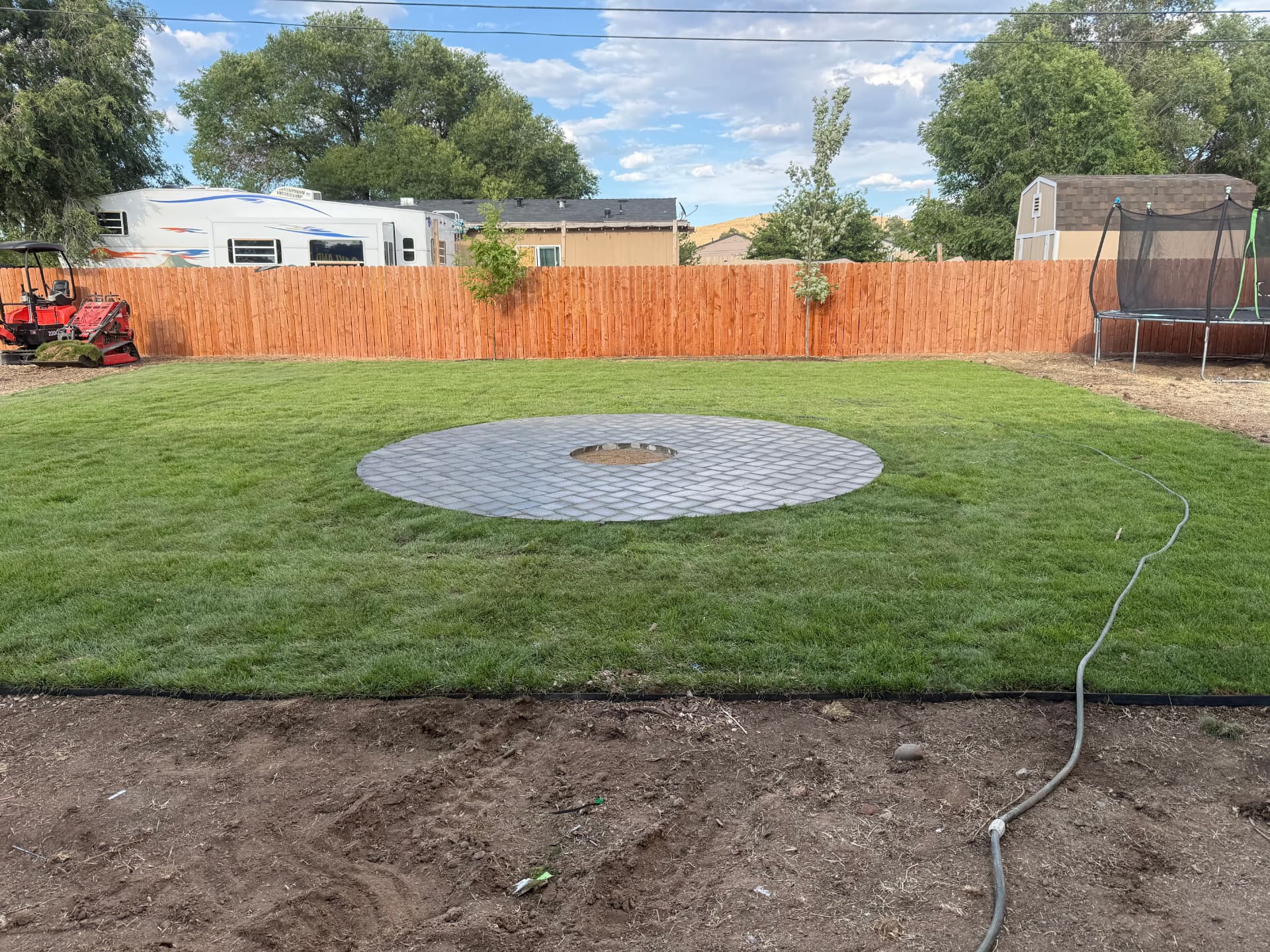 Finished backyard with new sod surrounding the circular paver patio
