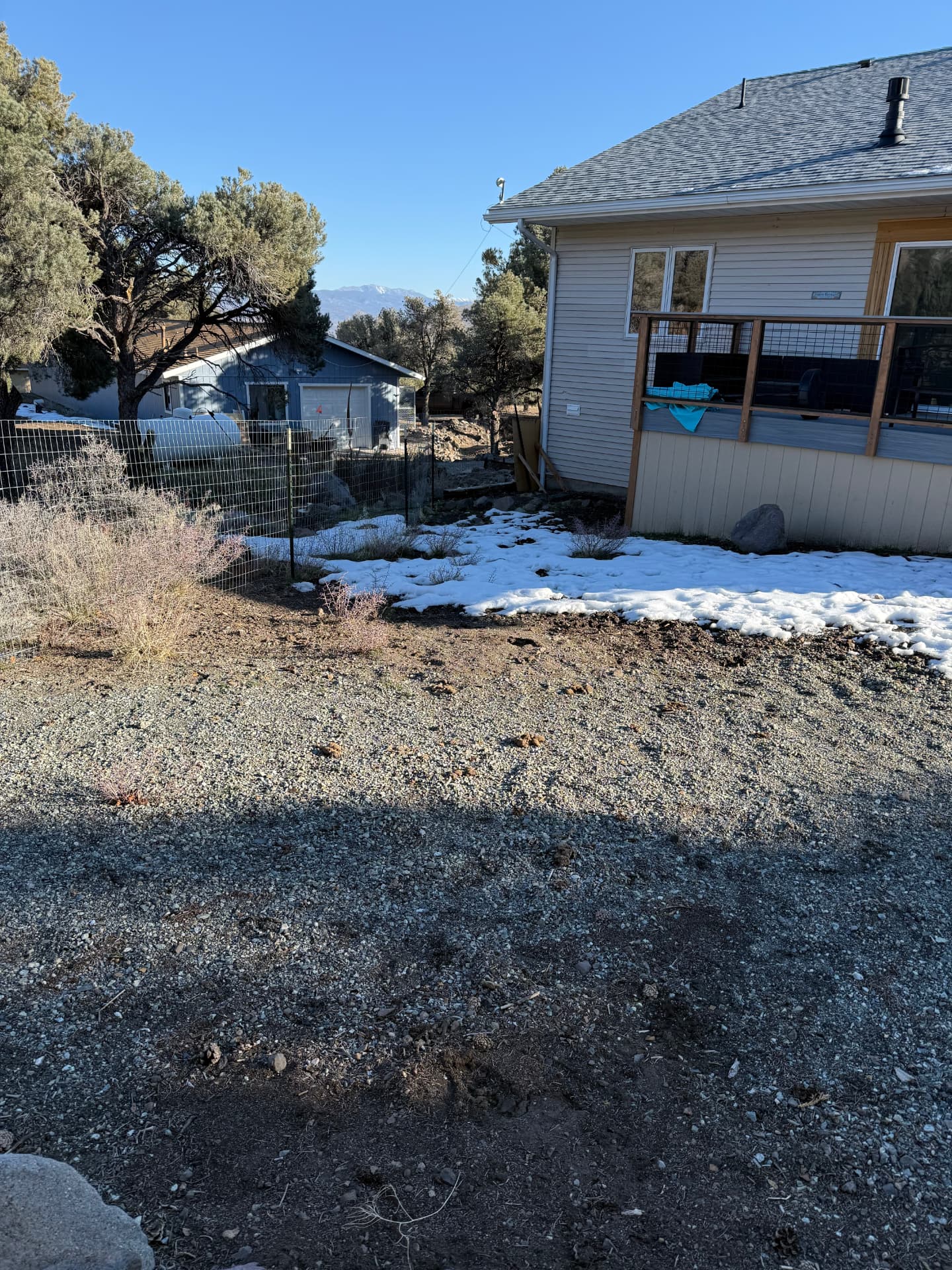 Side yard with dirt, gravel, and snow before hardscape installation