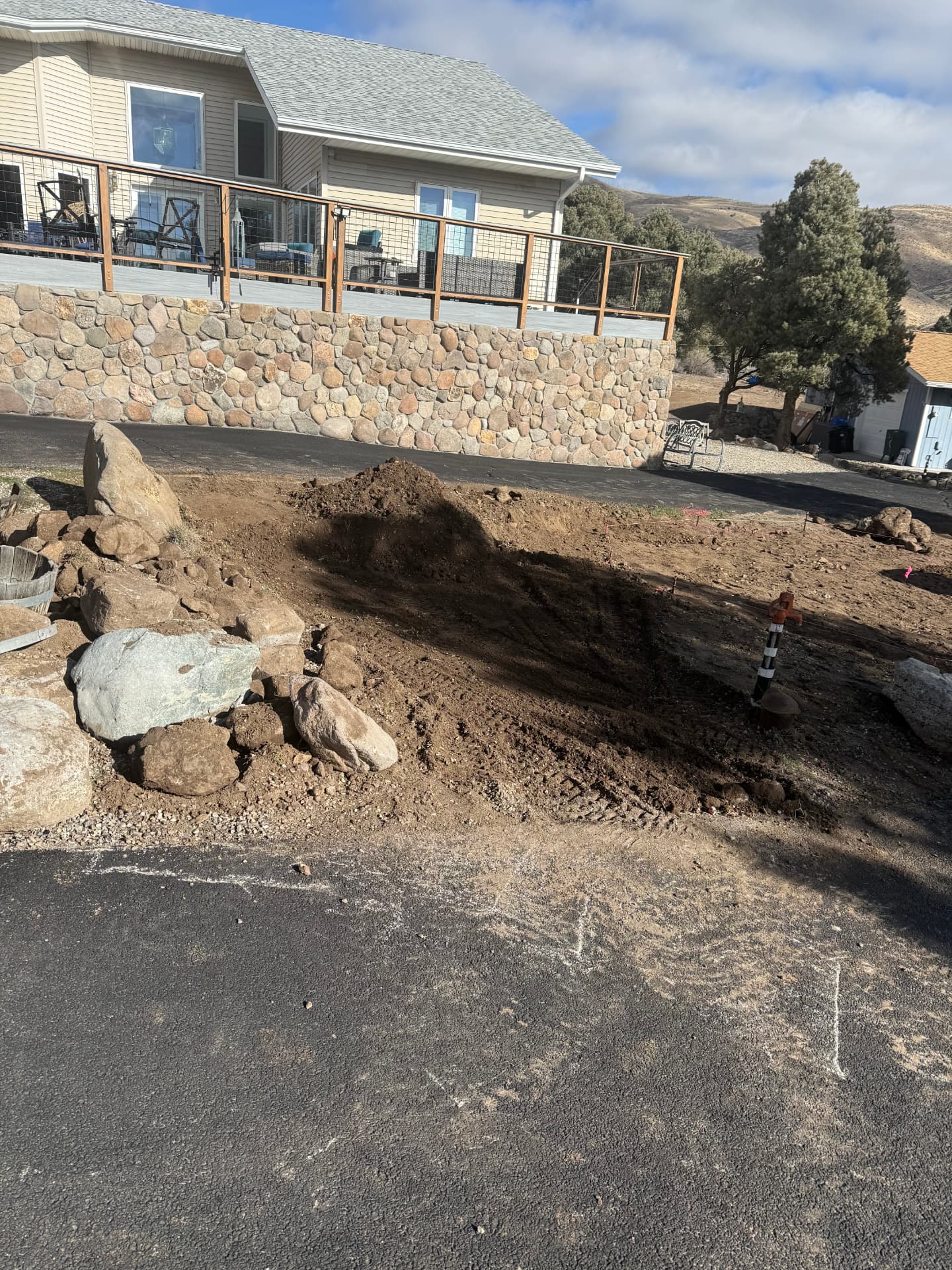 Excavated planting bed and grading below the stone-faced deck wall