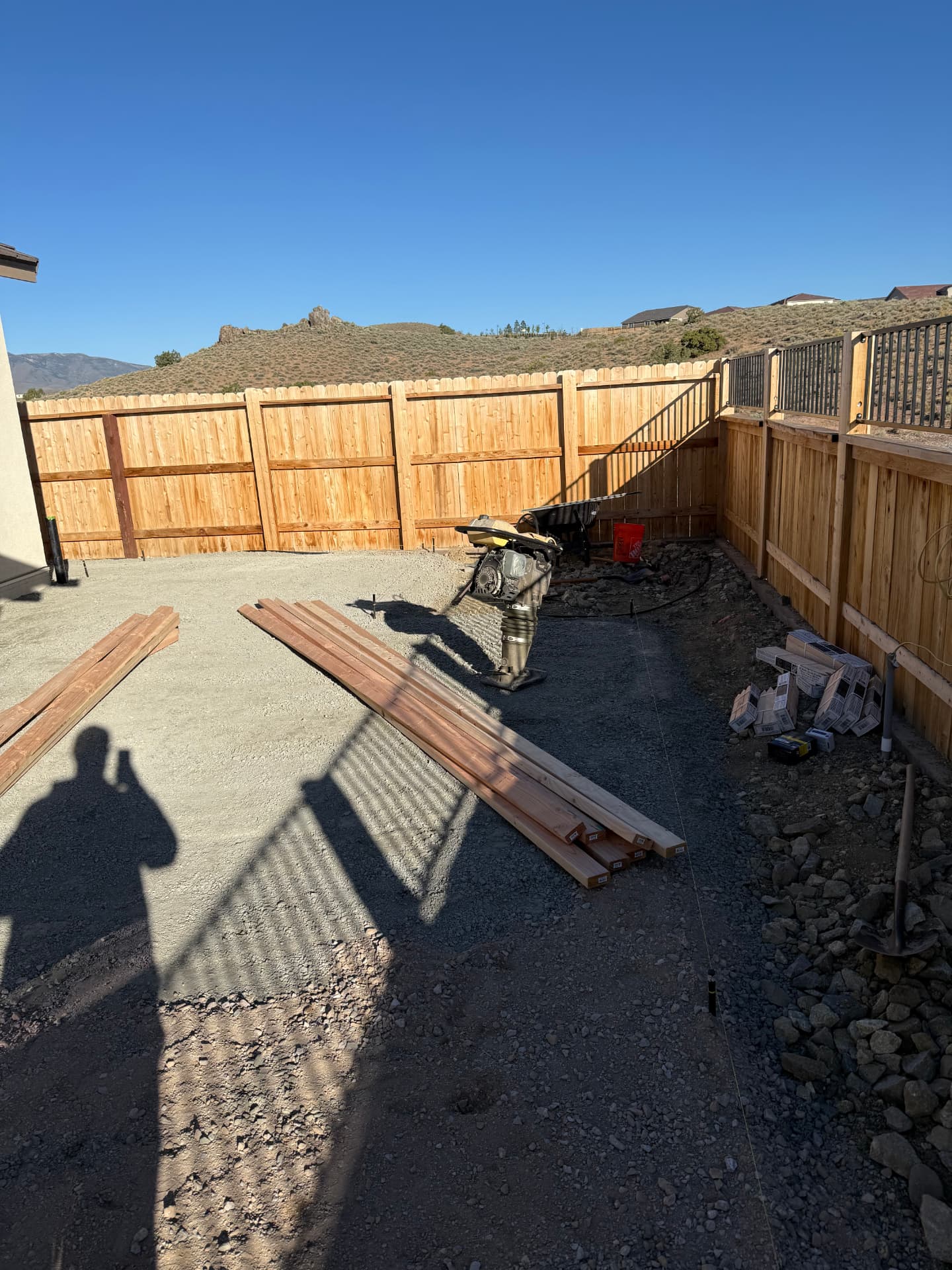 Compacted base and lumber staged for backyard forms