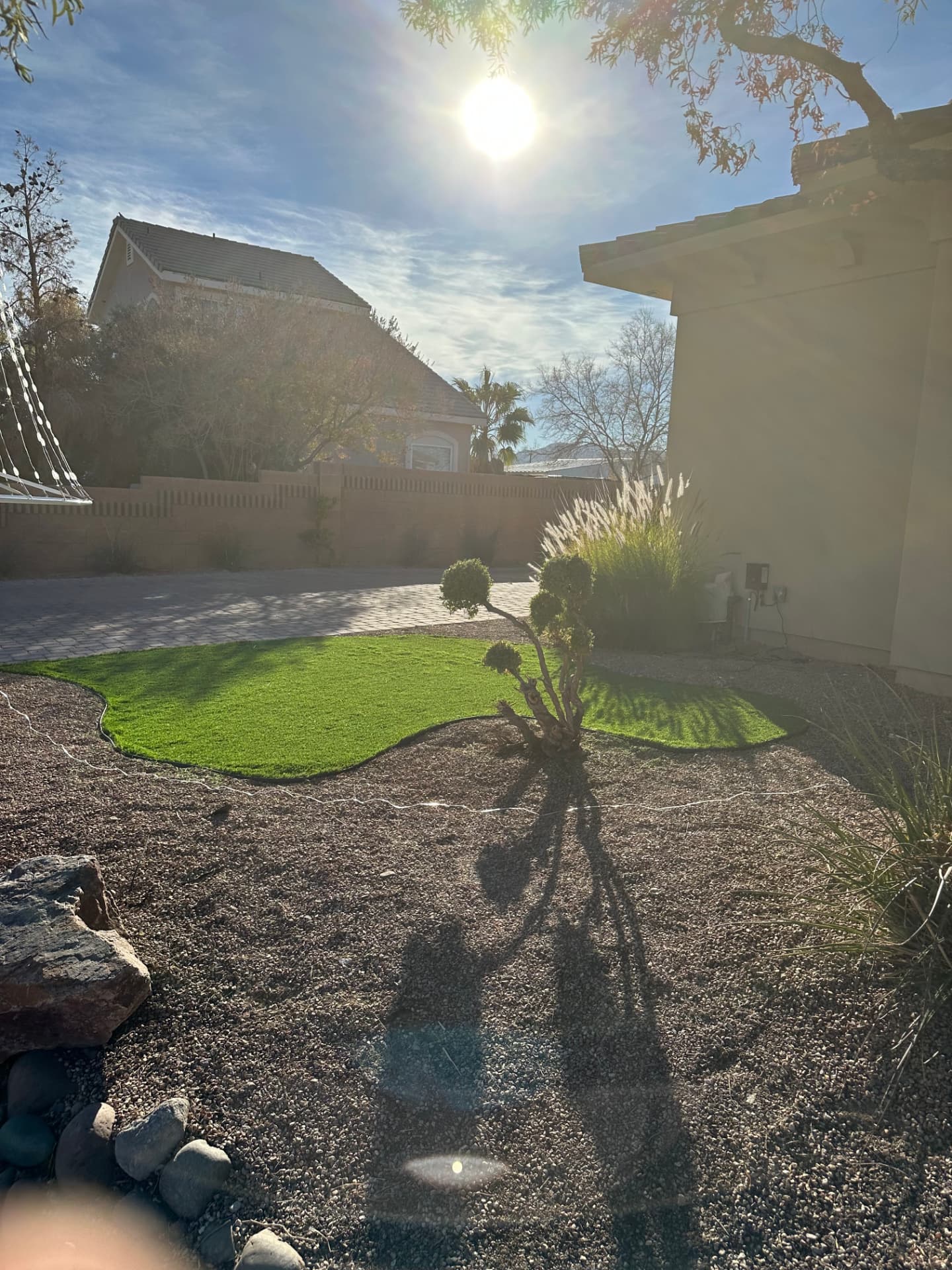 Front yard turf islands and gravel beds beside the paver driveway
