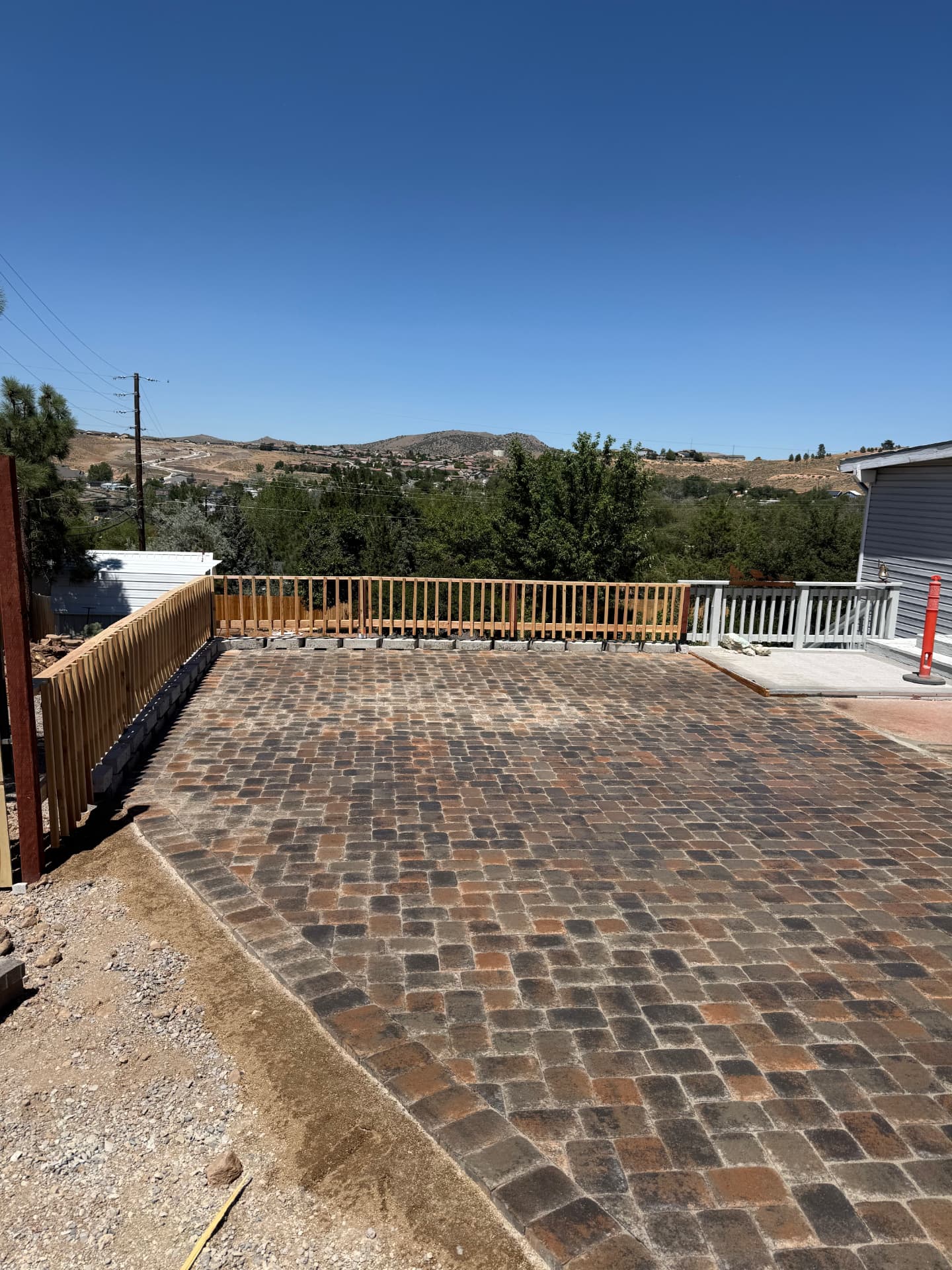 Completed paver patio and block retaining wall along the fence line