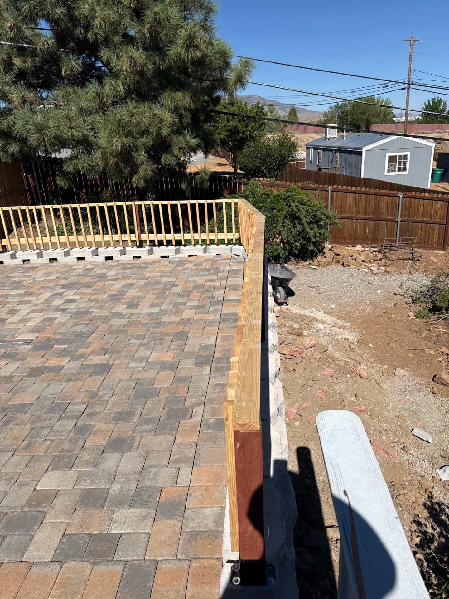Paver patio with cedar railing and block wall under construction