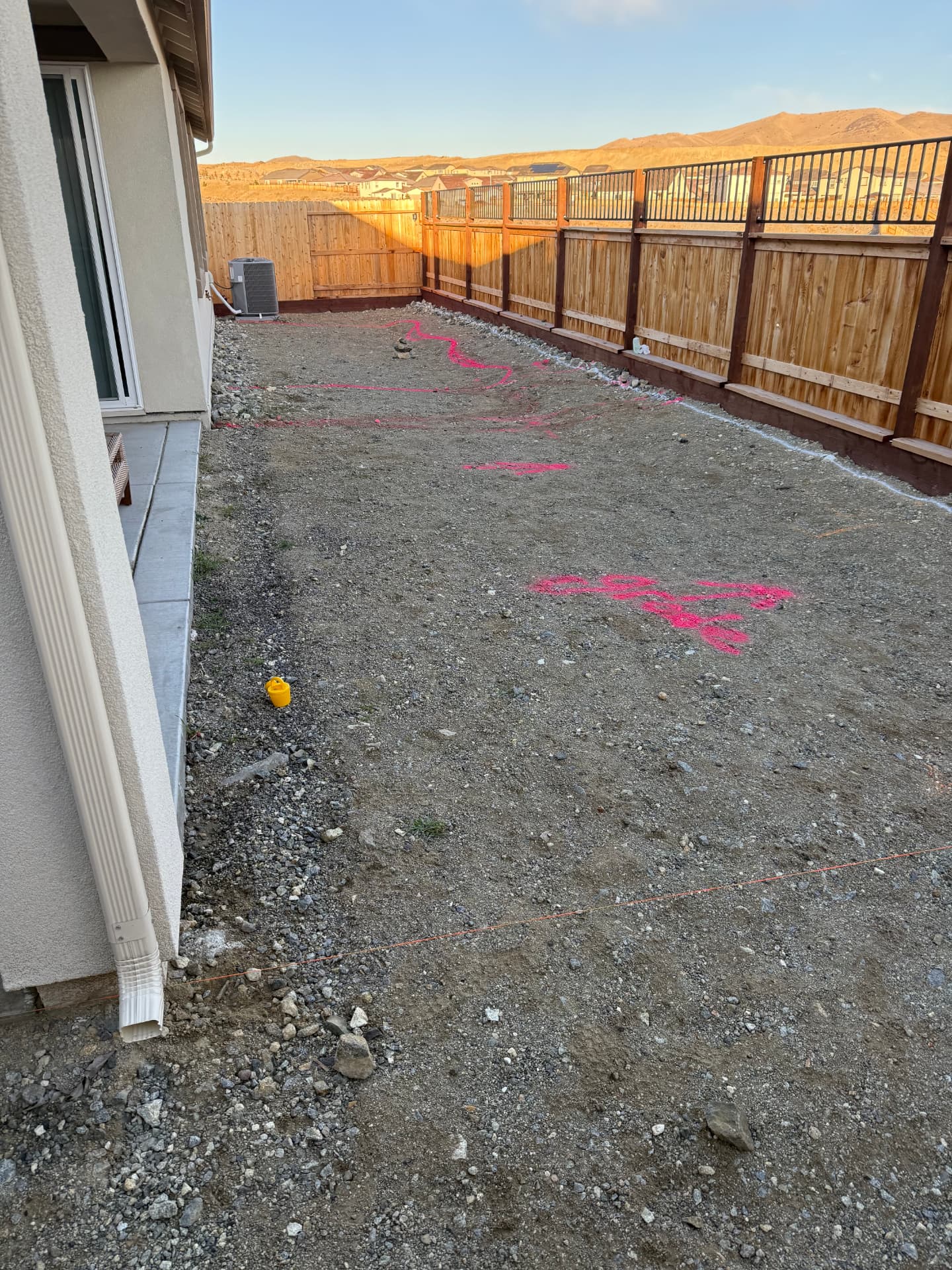 Bare backyard graded dirt with pink layout paint and mountain views