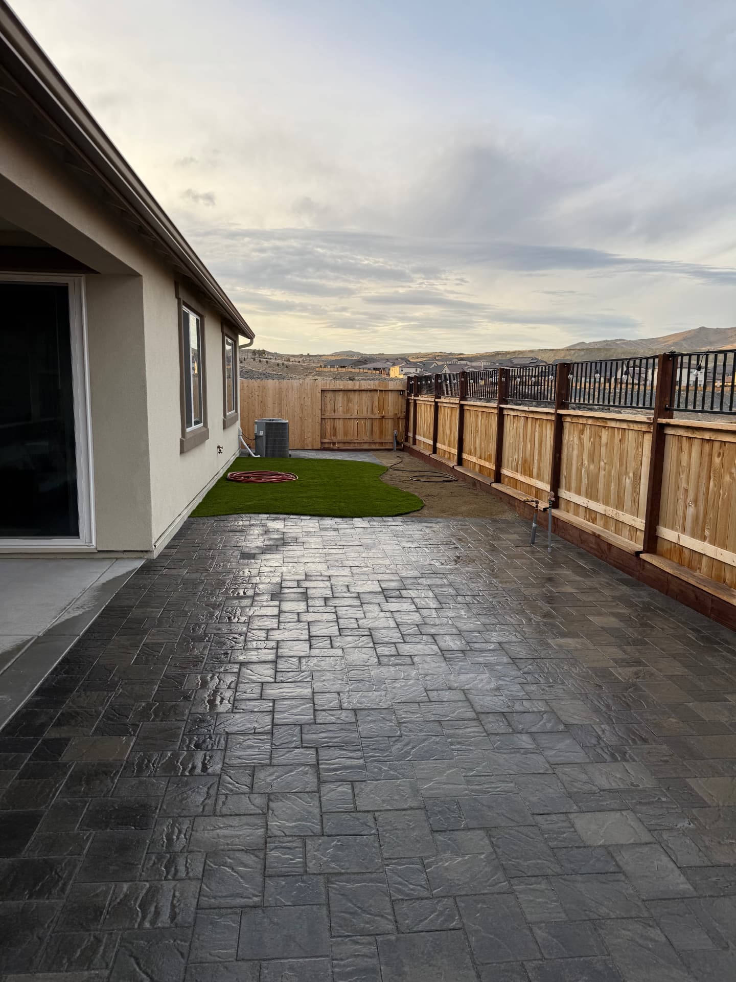 Wide finished backyard patio with turf lawn and valley views