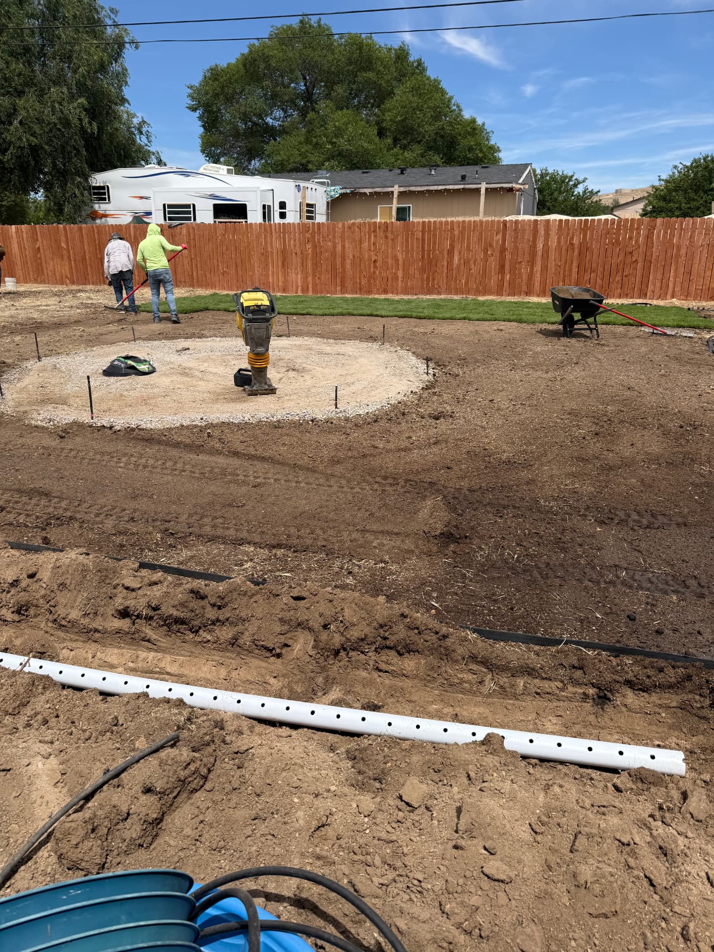 Compacting the gravel base for a circular paver patio in the backyard
