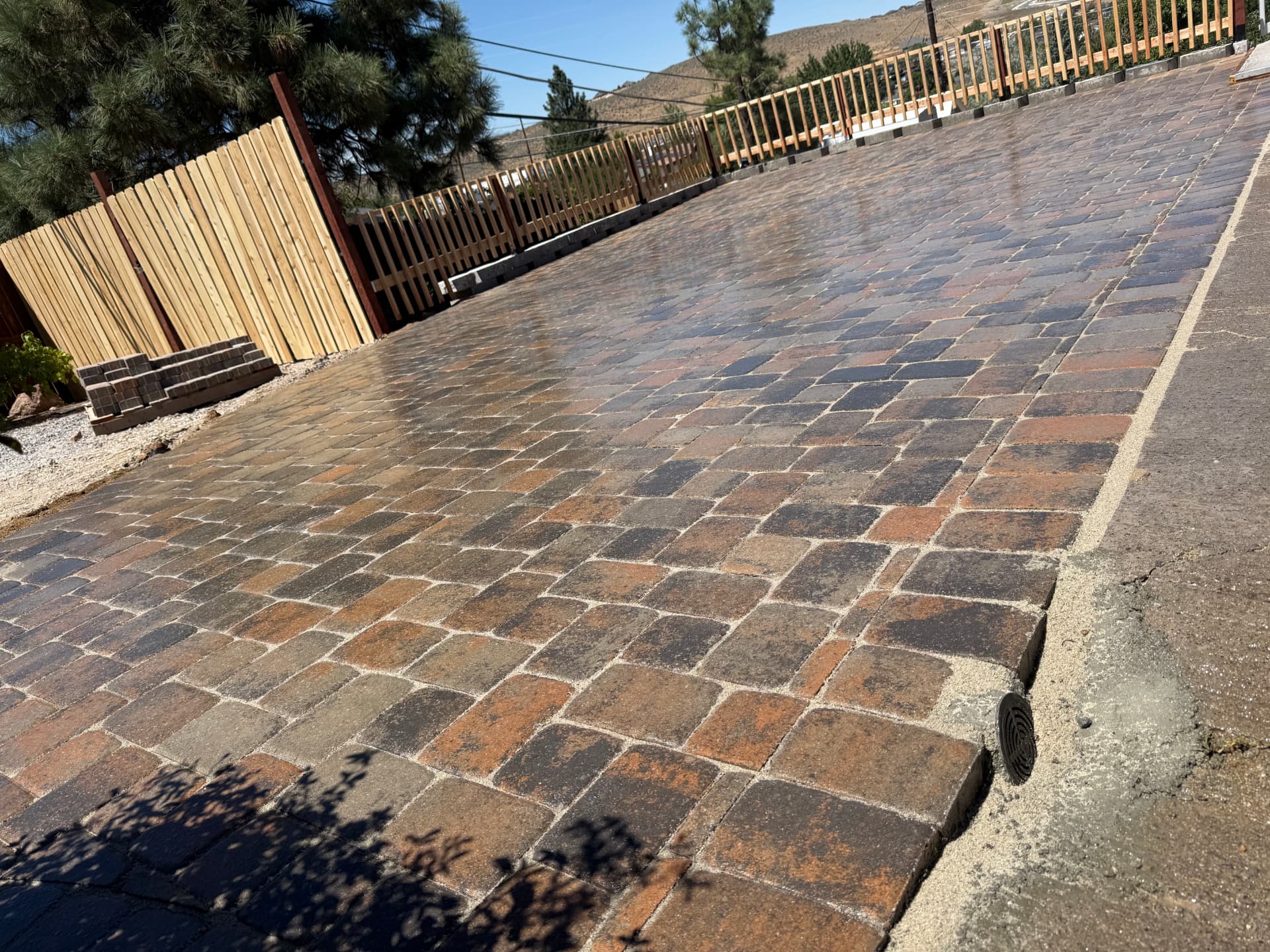 Completed paver driveway extension with cedar fence and hillside views