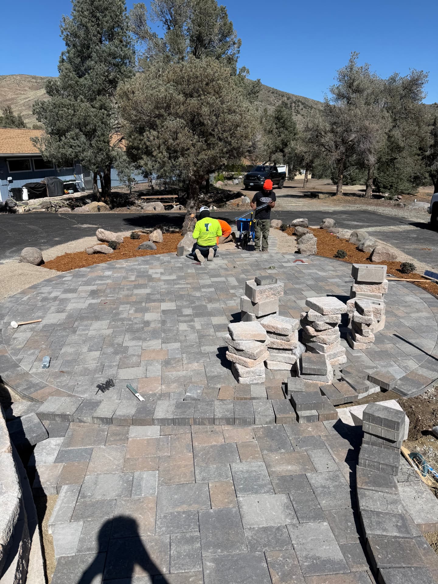Crew finishing the circular patio with a stone fire pit going in