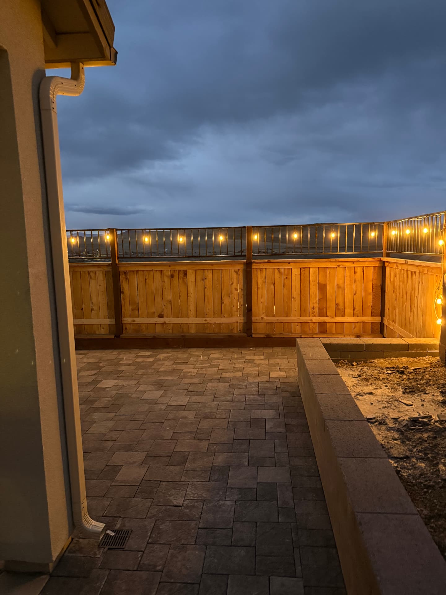 Evening view of the finished patio with string lights and block wall