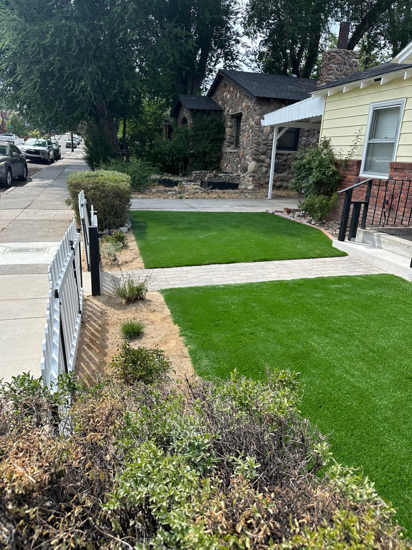 Finished front yard with synthetic turf, paver walkway and white picket fence