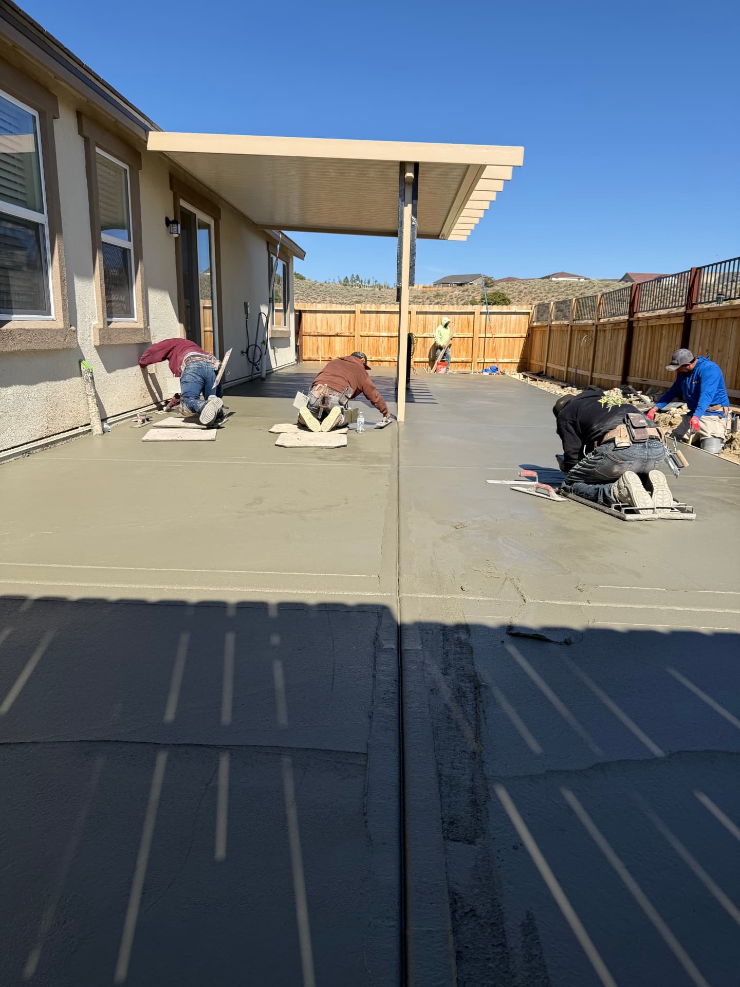 Crew finishing the freshly poured backyard concrete patio