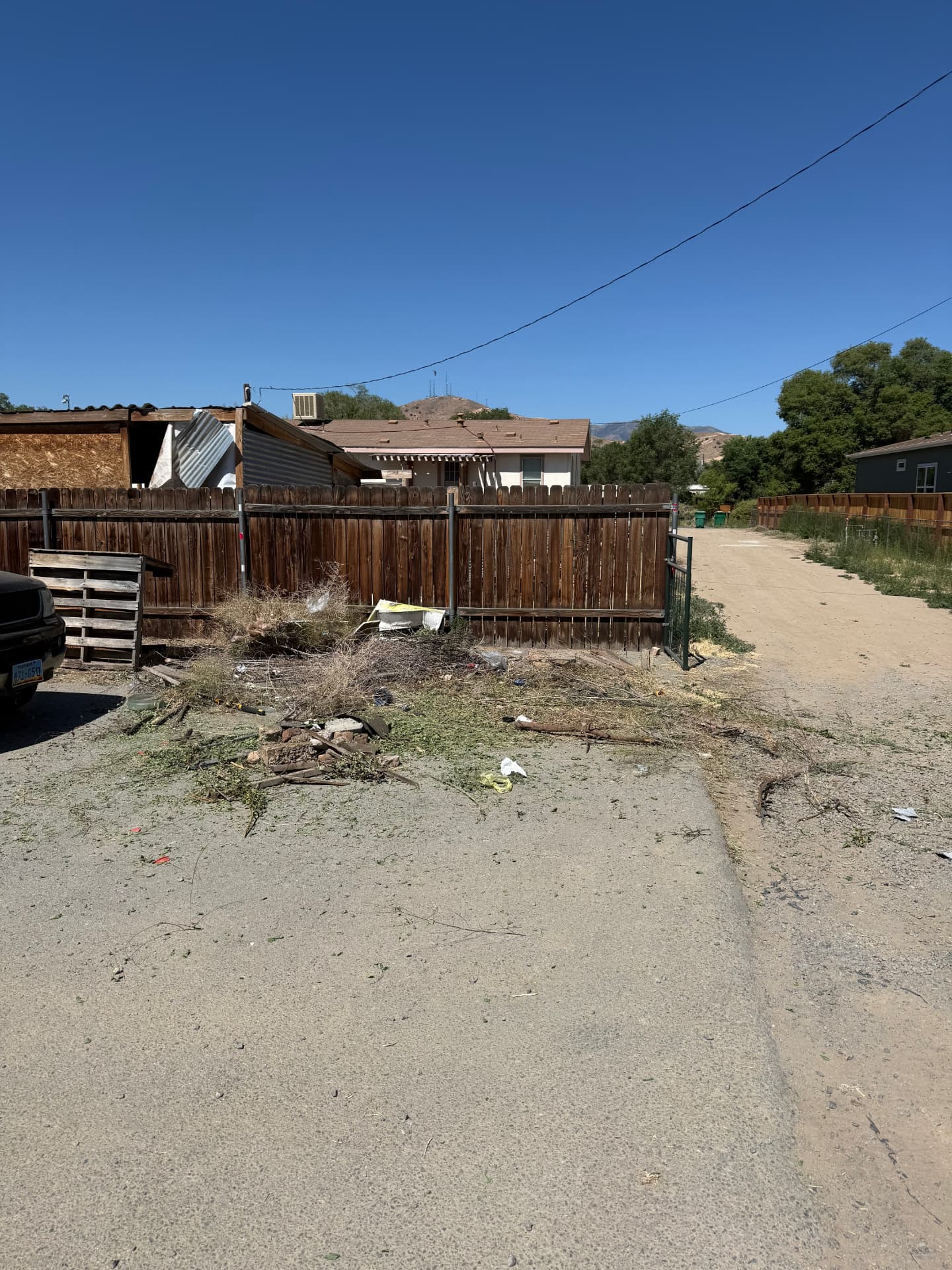 Unpaved driveway and side yard with debris before hardscape work