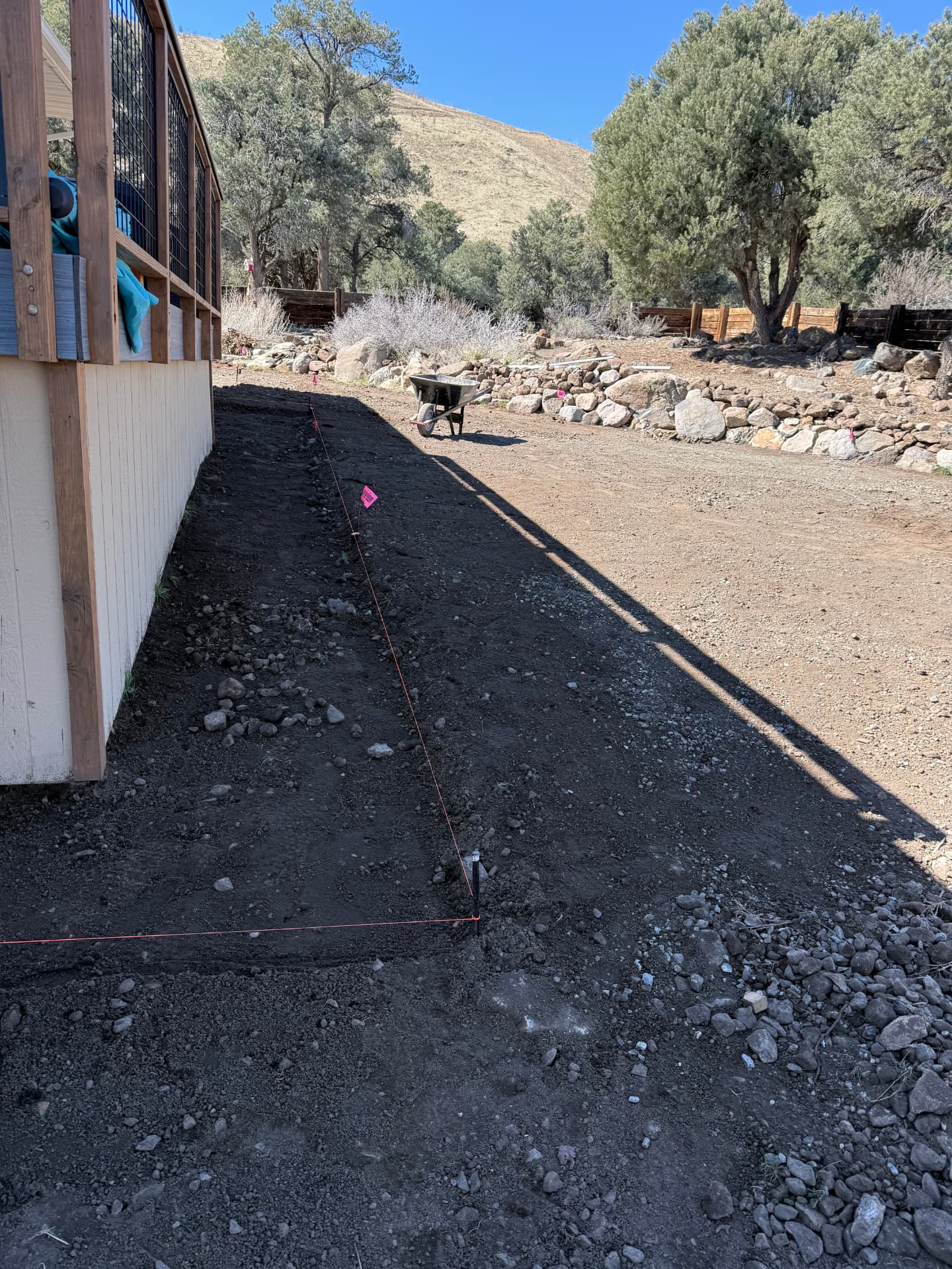 Excavated strip along the house with string lines set for the new walkway
