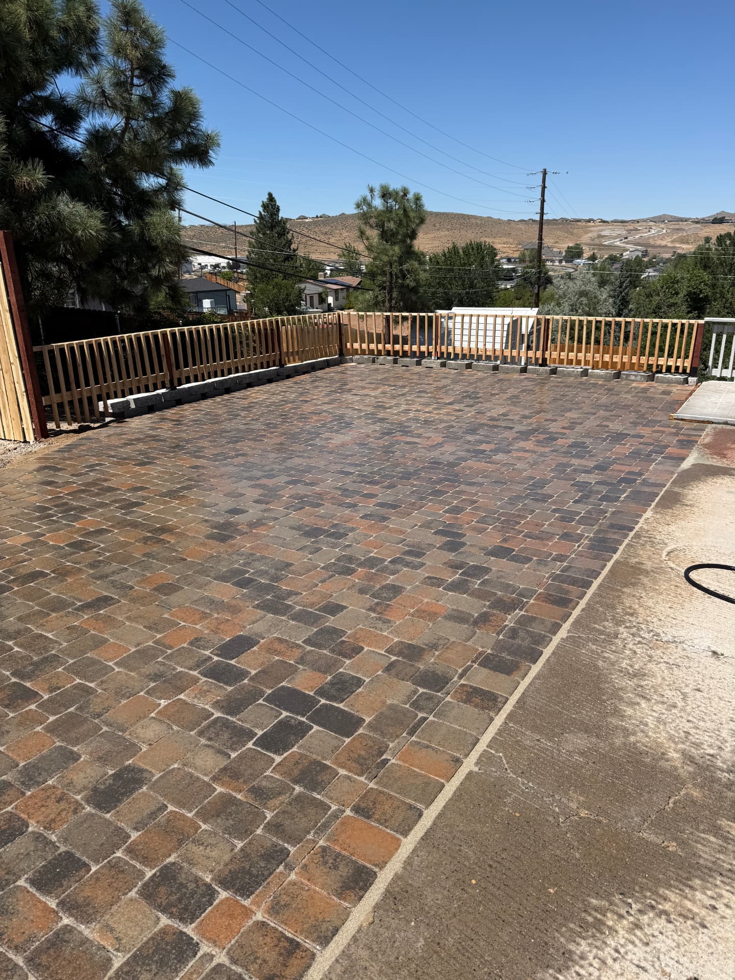 Finished cobblestone paver patio with cedar railing and Reno hillside views