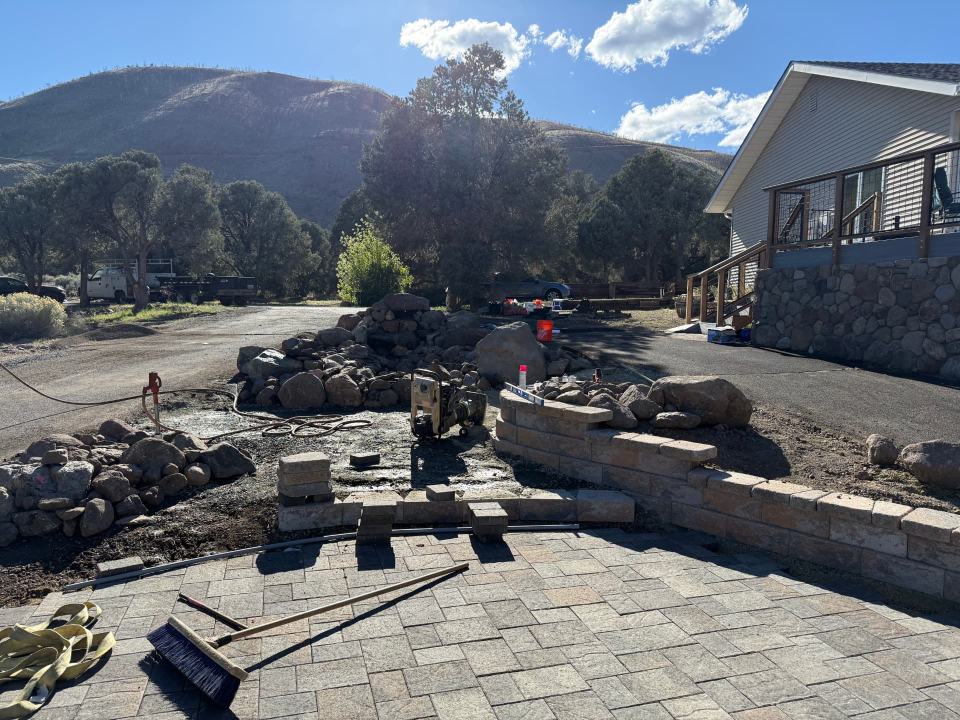 Finished paver patio, seat wall, and boulder water feature below the deck
