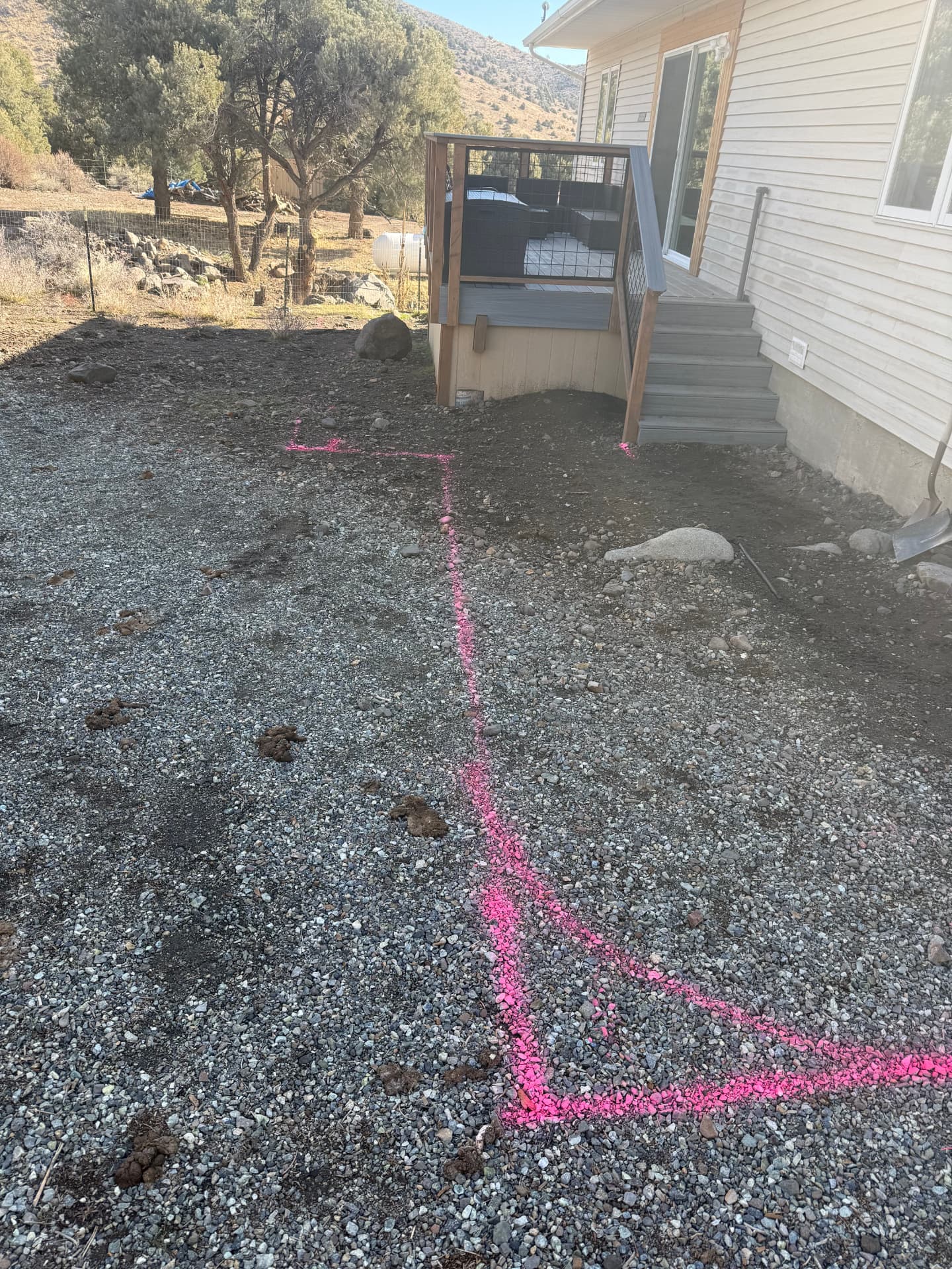 Backyard graded with pink layout paint marking the new patio footprint